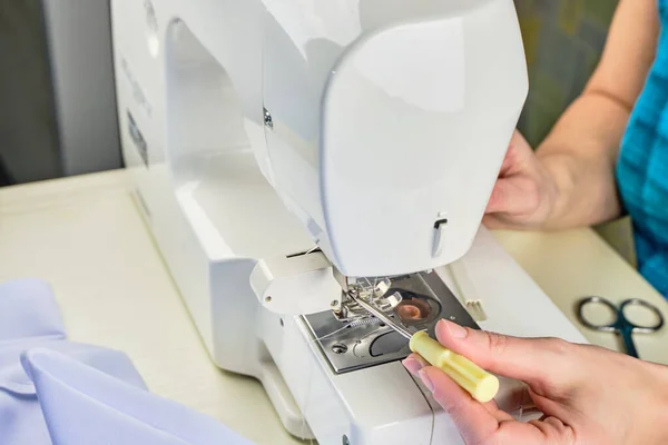 Manos femeninas haciendo trabajos de mantenimiento en una máquina de coser doméstica Fotos de stock