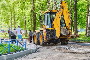 Traktör ve işçiler yolu onarıyor. Rusya.