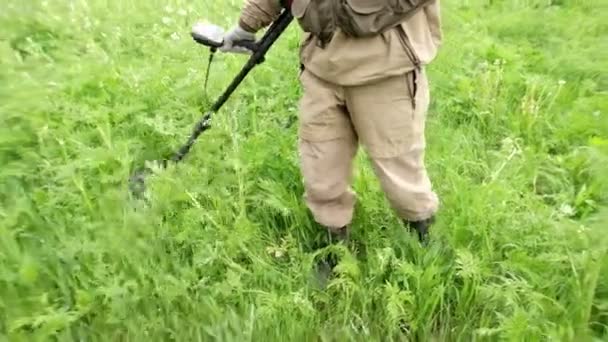 Slow-motion. A man holds a device, a metal detector in his hand, works in a meadow, a field, looking for treasure, coins, artifacts. Russia, Vladimir, June 26, 2021 — Stock Video