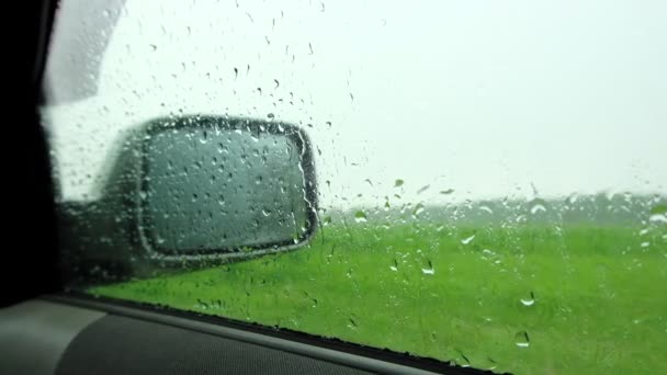 Gouttes de pluie sur la fenêtre de la voiture, gouttes de pluie coulent dans le verre des voitures, il pleut à l'extérieur de la voiture. — Video