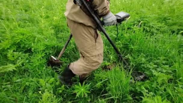 Un hombre sostiene un dispositivo, un detector de metales en su mano, cava un agujero con una pala, trabaja en un prado, en un campo, buscando tesoros, monedas, artefactos. Rusia. — Vídeo de stock