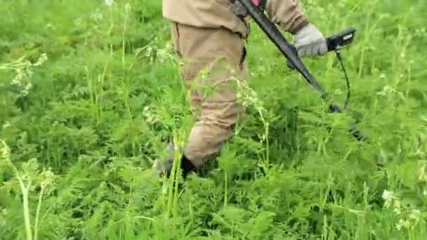 Un uomo tiene in mano un dispositivo, un metal detector, lavora in un prato, in un campo, alla ricerca di tesori, monete, manufatti. Russia, Vladimir, 26 giugno 2021 — Video Stock