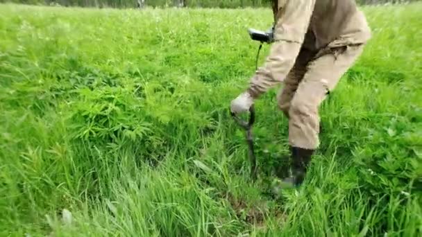 A man holds a device, a metal detector in his hand, digs a hole with a shovel, works in a meadow, in a field, looking for treasures, coins, artifacts. Russia. — Stock Video