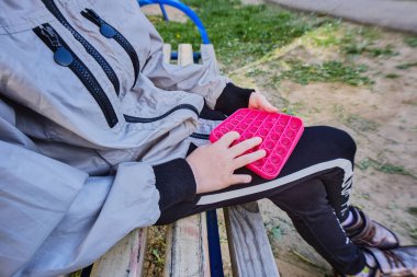 Mutlu küçük kız onunla oynar, parkta oyun parkında bir bankta oturur. Popit 7-9 yaşındaki bir kızın ellerinde..