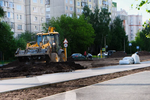 Sárga traktor javítja az utat. Oroszország, Vlagyimir, 2021. június 2. Útépítés a városban. Ipari berendezések — Stock Fotó