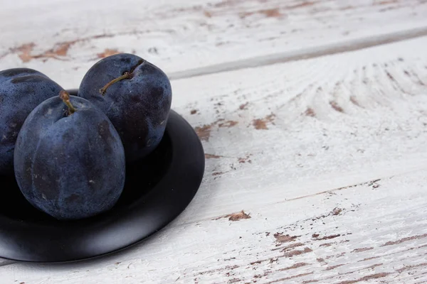 Beyaz ahşap masada mavi erikler