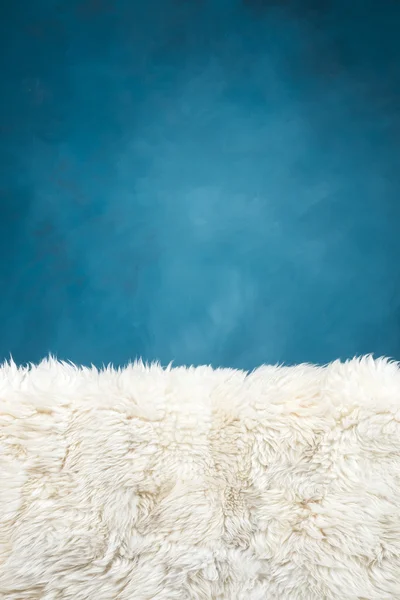 Fehér szőr szőnyeg és a kék festett fal — Stock Fotó