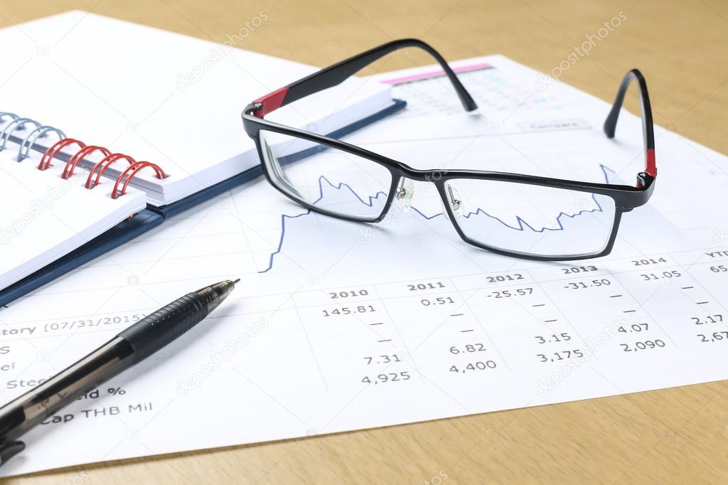 pen, notebook, glasses and financial report 