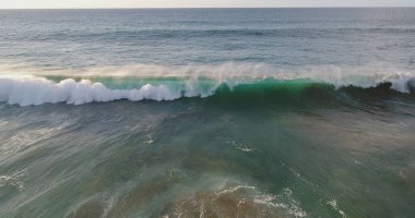 Kıyı şeridinde gün batımında kayalıkları, renkleri ve deniz fark ediliyor.