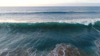 Kıyı şeridinde gün batımında kayalıkları, renkleri ve deniz fark ediliyor.