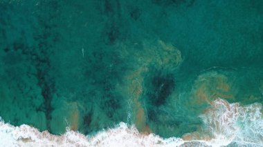 Kıyı şeridinde gün batımında kayalıkları, renkleri ve deniz fark ediliyor.