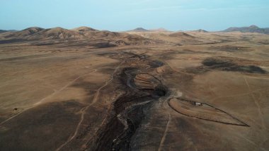 Kıyı şeridinde gün batımında kayalıkları, renkleri ve deniz fark ediliyor.