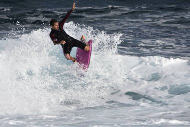 Genç bir sörfçü denizdeki dalgalarda