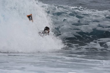 Siyah mayo giyen ve sörf tahtası olan bir adam.