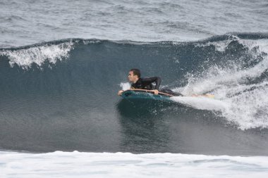 Denizde sörf yapan bir sörfçü