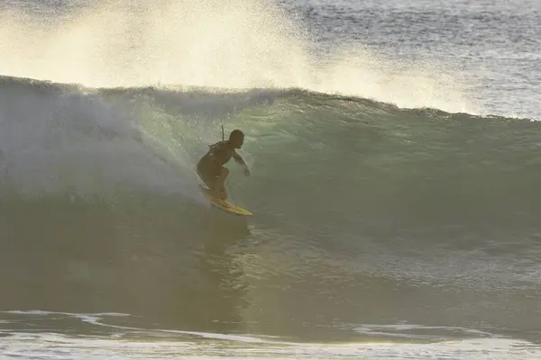 Arka planda dalga olan bir sörfçü.