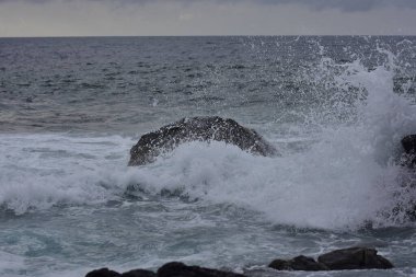 Kara kayanın üzerinde deniz dalgası