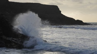 Dalgalar kayalık bir sahilde kırılıyor