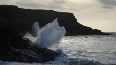 Dalgaların güzel bir görüntüsü denizdeki kayalıklara çarpıyor.