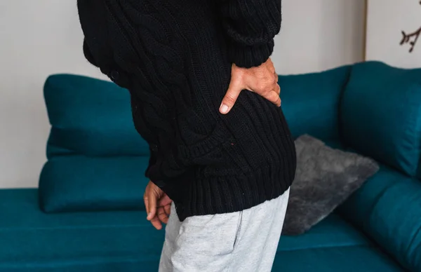 Yaşlı bir adam koltuktan kalktıktan sonra sırtına dokunur. Sırtındaki şiddetli ağrıdan dolayı..