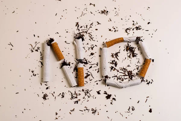 Word NO written with pieces of broken cigarettes, on a white surface, symbolizing the rejection of smoking and the desire for a world without smoke. May 31 international no tobacco day