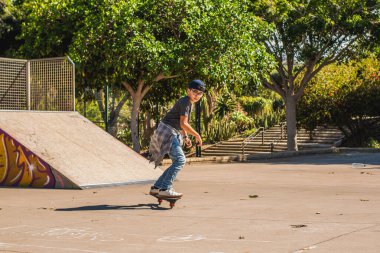 Paten parkında kaykayıyla kaykay yapan beyaz bir çocuk.