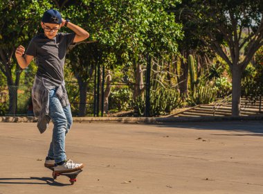 Paten parkında kaykayıyla kaykay yapan beyaz bir çocuk.