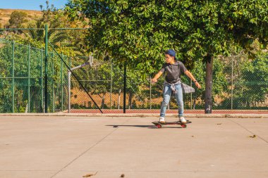 Paten parkında kaykayıyla kaykay yapan beyaz bir çocuk.