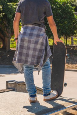 Arkadan çekilen tanınmamış genç, kaykay parkından bir engeli aşmaya hazırlanıyor.