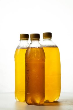 Beyaz arka planda şeffaf plastik şişelerde köpüklü bira.