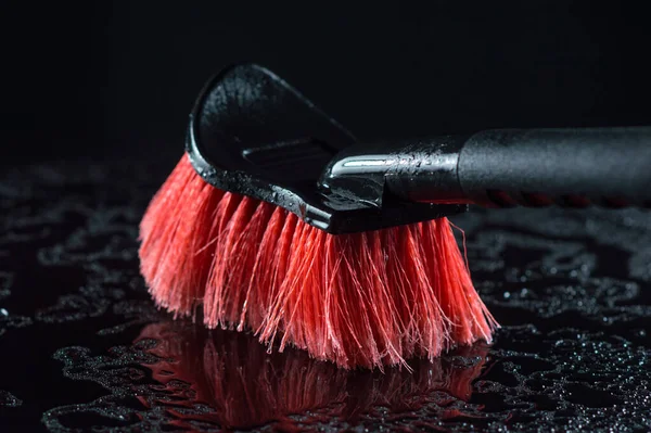 red car wash brush with a soft black handle on a black background