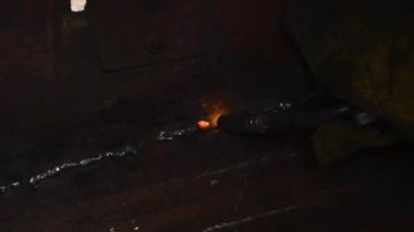 Karanlıktaki kaynakçı kaynak makinesiyle metalde kaynak yapıyor.
