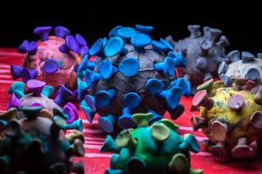 Kırmızı zemin üzerinde plasticine coronavirus 'un soyut çok renkli figürleri