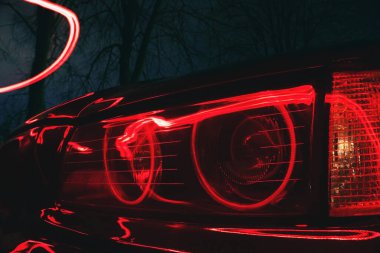  Gece eski bir arabanın uzun süre maruz kalması üzerine kırmızı ışıkla aydınlatılan araba farları.