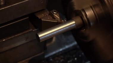 Eski bir torna tezgahında bir robot karanlık bir atölyede metal bir parçayı oyuyor.