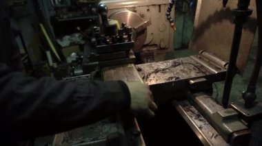 Eski bir torna tezgahında bir robot karanlık bir atölyede metal bir parçayı oyuyor.