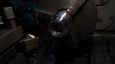 Eski bir torna tezgahında bir robot karanlık bir atölyede metal bir parçayı oyuyor.