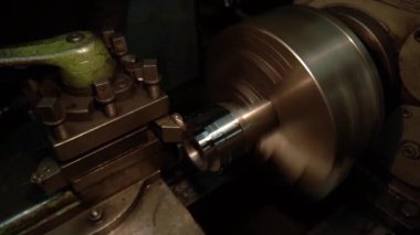 Eski bir torna tezgahında bir robot karanlık bir atölyede metal bir parçayı oyuyor.