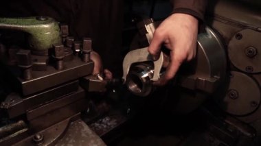 Eski bir torna tezgahında bir robot karanlık bir atölyede metal bir parçayı oyuyor.