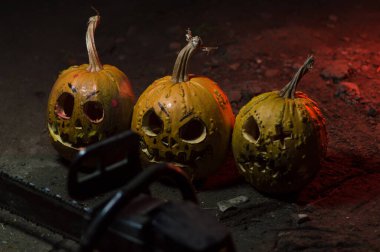 autumn holiday Halloween 2025 scary orange pumpkins with a working chainsaw in a blood red light in the dark