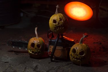 autumn holiday Halloween 2025 scary orange pumpkins with a working chainsaw in a blood red light in the dark