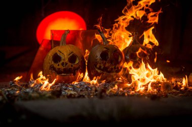 autumn holiday Halloween 2025 scary orange pumpkins burning in fire and smoke with blood red light in the dark