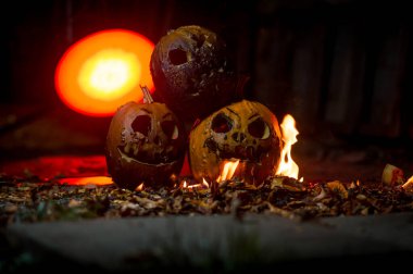 autumn holiday Halloween 2025 scary orange pumpkins burning in fire and smoke with blood red light in the dark