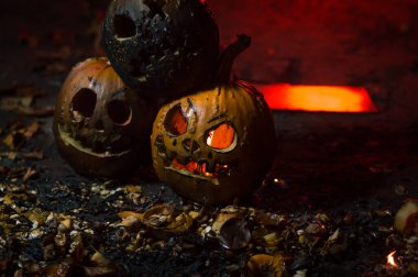 autumn holiday Halloween 2025 scary orange pumpkins burning in fire and smoke with blood red light in the dark