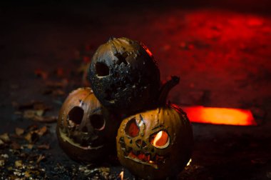autumn holiday Halloween 2025 scary orange pumpkins burning in fire and smoke with blood red light in the dark