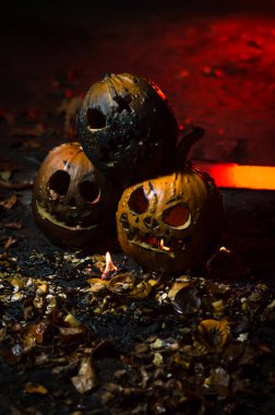 autumn holiday Halloween 2025 scary orange pumpkins burning in fire and smoke with blood red light in the dark