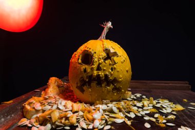 art scary Halloween with pumpkins and an old kerosene lamp in a red light preparation for the celebration in a dark room
