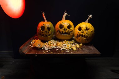 art scary Halloween with pumpkins and an old kerosene lamp in a red light preparation for the celebration in a dark room