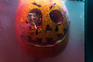 autumn holiday Halloween 2025 scary orange pumpkins drowning in water with bubbles and splatters in blood red light in the dark