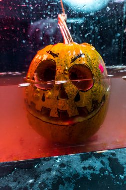 autumn holiday Halloween 2025 scary orange pumpkins drowning in water with bubbles and splatters in blood red light in the dark